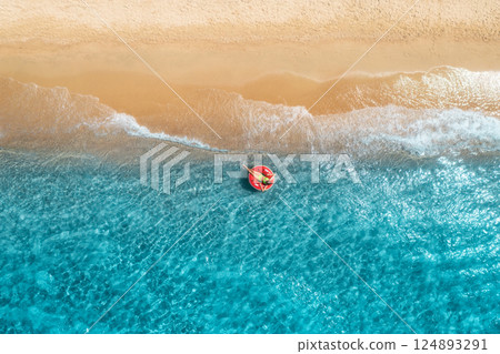 Aerial view of a young woman swimming with red swim ring Aerial view of a young woman swimming with red swim ring 124893291