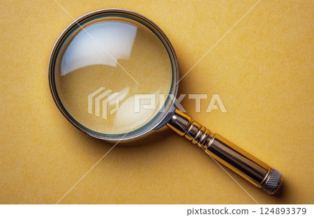 Magnifying glass on a bright yellow background showcasing details in clear focus 124893379
