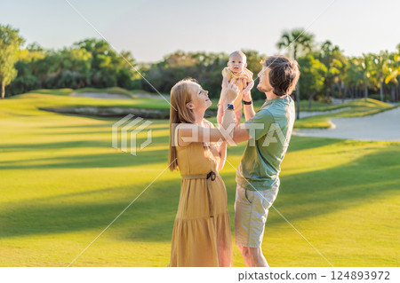 Loving parents with their newborn baby on a meadow in the park. Happy family enjoying nature, bonding, and peaceful outdoor moments. Parenthood, love, and family connection concept 124893972