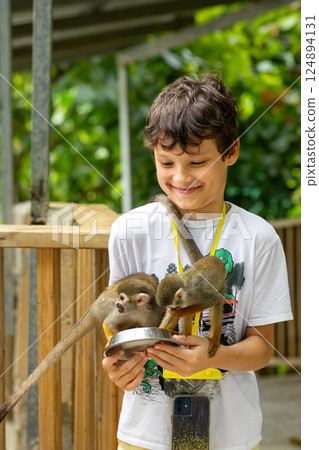 Young traveler is feeding a monkey from hands in the zoo. 124894131