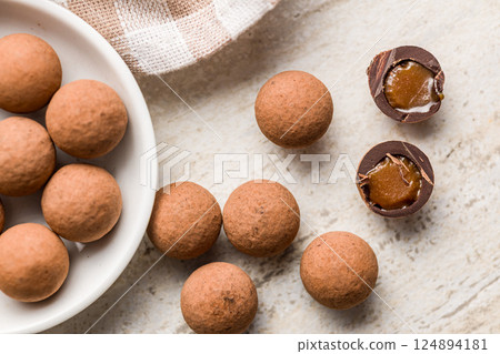 Chocolate truffles with cocoa powder and caramel filling on kitchen table. Top view. 124894181