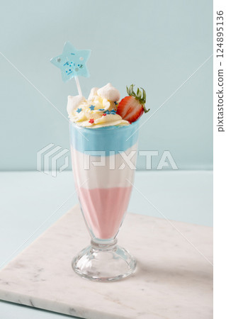 Layered milkshake or sweet dessert in red, white and blue colors garnish strawberry and blueberries on pastel blue background. Crazy Summer dessert for Independence Day for kids party. Layered milkshake or sweet dessert in red, white and blue colors garnish strawberry and blueberries on pastel blue background. Crazy Summer dessert for Independence Day for kids party. 124895136