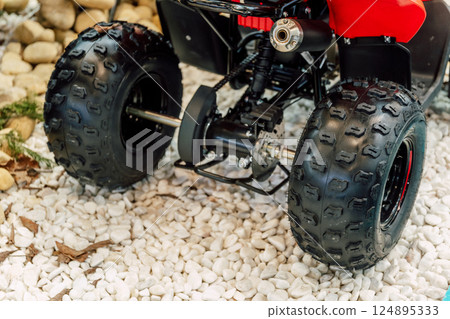 off-road quad bike wheel on a pile of rocks. off-road studded tire on mountain boulders off-road quad bike wheel on a pile of rocks. off-road studded tire on mountain boulders 124895333