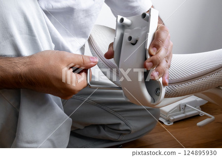 Male assembling office chair using allen wrench in bright room Male assembling office chair using allen wrench in bright room 124895930