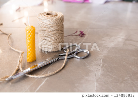 Crafting essentials. Twine, scissors, wax candle on marble surface 124895932