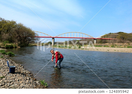 一位穿著防水褲的漁民用抄網捕捉河裡的昆蟲 124895942