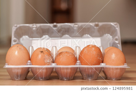 Ten mouldy eggs in plastic packaging, mildew growing on shell as they were stored improperly in wet fridge for long 124895981