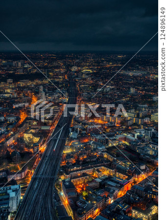 Aerial night view of east London, wide railway track with one train on it in middle Aerial night view of east London, wide railway track with one train on it in middle 124896149