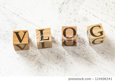 Four wooden cubes with word VLOG (meaning Video Blog) on white working board. 124896341