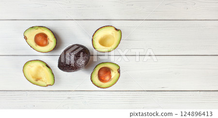 Ripe brown avocado - Hass bilse variety - halved and arranged on white boards desk, view from above, space for text right side 124896413