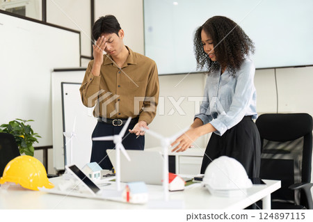 Sustainability and Collaboration. A man and woman in a modern office discussing renewable energy solutions actively. 124897115