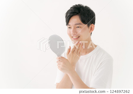 Man looking in a hand mirror 124897262