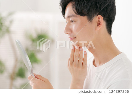 Man looking in a hand mirror 124897266