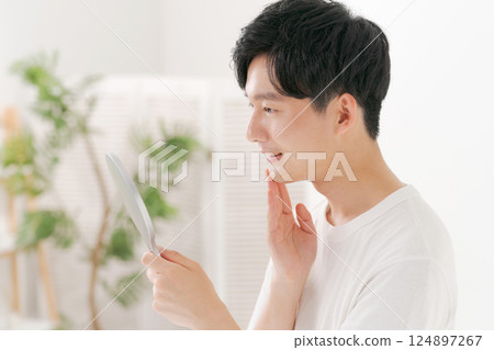 Man looking in a hand mirror 124897267