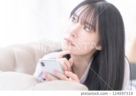 一位年輕女子使用智慧型手機選擇診所 一位年輕女子使用智慧型手機選擇診所 124897319