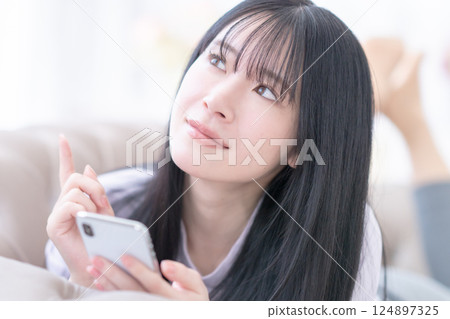 一位年輕女子使用智慧型手機選擇診所 一位年輕女子使用智慧型手機選擇診所 124897325