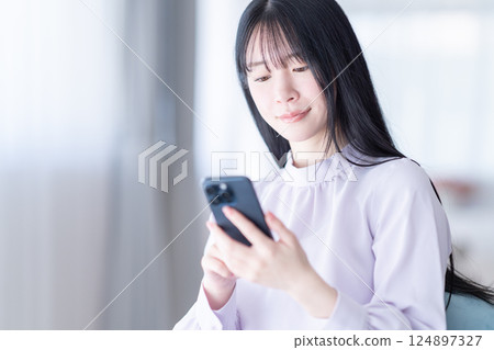 一位年輕女子每天用智慧型手機查看自己的儲蓄金額 一位年輕女子每天用智慧型手機查看自己的儲蓄金額 124897327