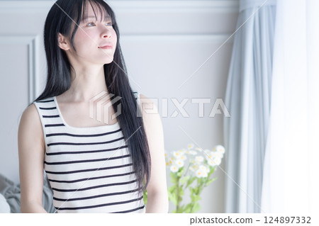 A young woman wearing a refreshing tank top using a computer 124897332