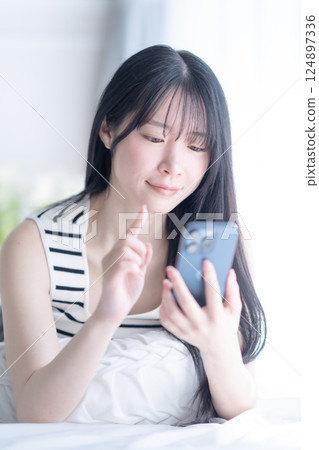 一位身穿清爽背心、使用智慧型手機的自然美女的圖片 124897336