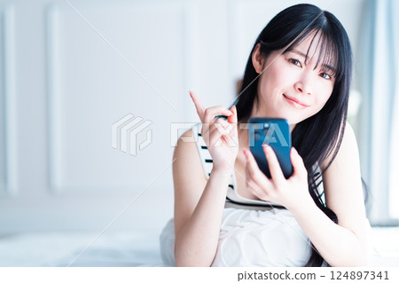 A young woman holding a smartphone and posing for a recommendation 124897341