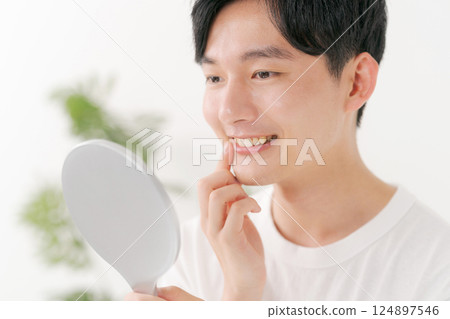 Man looking in a hand mirror Man looking in a hand mirror 124897546