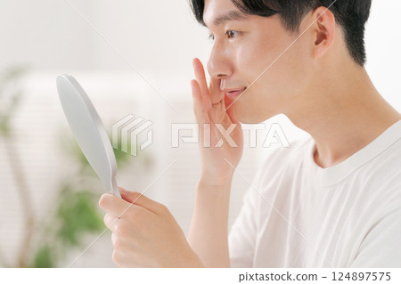 一位男士用手鏡進行皮膚護理 一位男士用手鏡進行皮膚護理 124897575