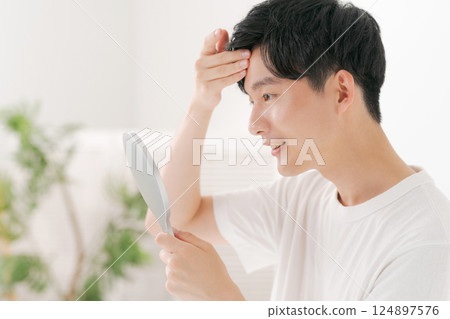 一位男士用手鏡進行皮膚護理 一位男士用手鏡進行皮膚護理 124897576