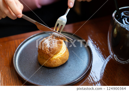 Hands eating a cream puff 124900364