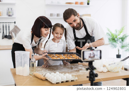 Caucasian family, man, woman in twenties, young girl child, baking cookies in kitchen 124902801