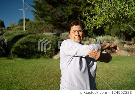 Senior woman stretching arm in sunny park Senior woman stretching arm in sunny park 124902828