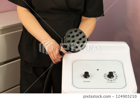 Therapist presenting cavitation handpiece above aesthetic control panel.Keywords: 124903210