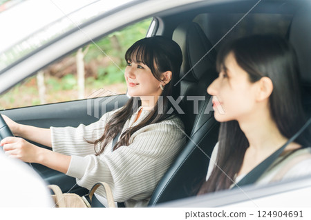 A woman driving a car and her female friend in the passenger seat 124904691