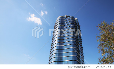 A tall and impressive building stands prominently against a clear blue sky 124905233