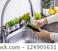 Woman hands washing a cucumber to prepare a fresh salad in the kitchen 124905631