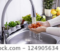 Woman hands washing fresh cherry tomatoes to prepare a fresh salad 124905634