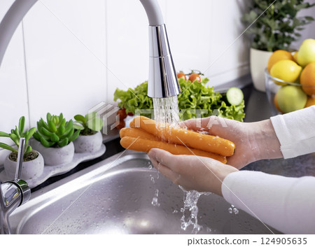 Woman hands washing fresh carrots in the kitchen 124905635