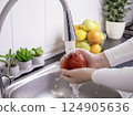 Woman hands washing fresh red apple in the kitchen 124905636