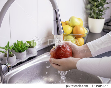 Woman hands washing fresh red apple in the kitchen 124905636