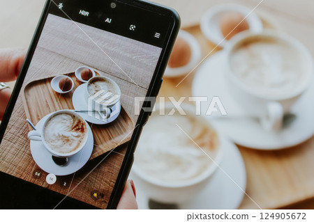 Making a phone photo of two white coffee cups with sweet pastry. Breakfast flat lay on phone screen. Make a photo of morning aroma coffee and dessert for social media. Americano with milk and biscuits Making a phone photo of two white coffee cups with sweet pastry. Breakfast flat lay on phone screen. Make a photo of morning aroma coffee and dessert for social media. Americano with milk and biscuits 124905672