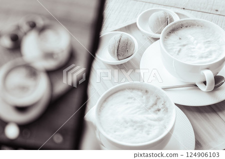 Making a phone photo of two white coffee cups with sweet pastry, monochrome. Breakfast flat lay on phone screen, black and white. Make a photo of morning aroma coffee and dessert for social media. 124906103
