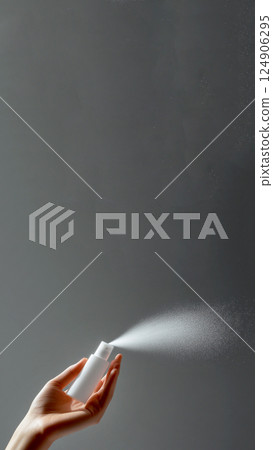 A refreshing mist of toner or lotion being sprayed from a hand, creating a splash against a soft grey background. hydration and skincare freshness, perfect for a social media reel or story 124906295