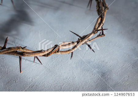 Jesus Crown of thorns projecting shadowy silhouette against textured gray surface, symbolizing spiritual pain and redemptive struggle good friday for Christian background, Easter concept 124907653