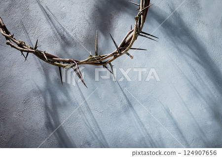 Crown of thorns projecting shadowy silhouette against textured gray surface, symbolizing spiritual pain and redemptive struggle good friday for Christian background, Easter concept 124907656