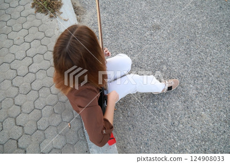 Girl Plays The Bass Instrument Sitting On The Step Near The Street At Evening 124908033