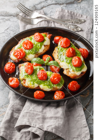 Grilled chicken margherita topped with melted mozzarella cheese, basil pesto and tomato close-up on pan. Vertical Grilled chicken margherita topped with melted mozzarella cheese, basil pesto and tomato close-up on pan. Vertical 124909165