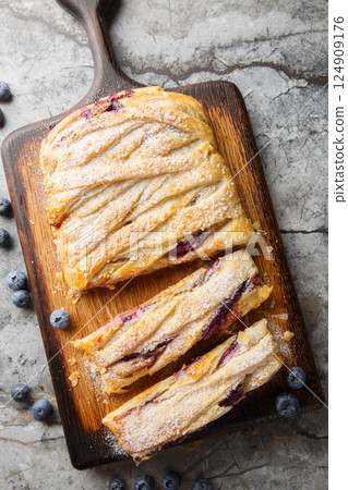 Puff pastry pie with blueberries and cream cheese close-up on wooden board. Vertical top view 124909176
