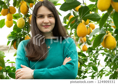 Woman in lemon orchard smiling and looking at camera Woman in lemon orchard smiling and looking at camera 124909331