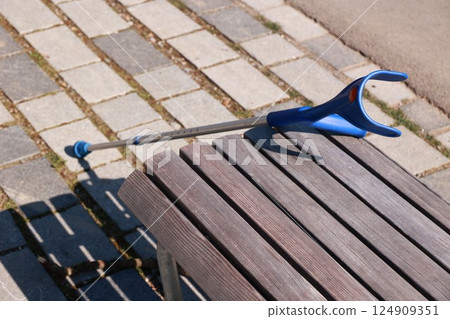 A blue and silver cane is leaning against a wooden bench A blue and silver cane is leaning against a wooden bench 124909351