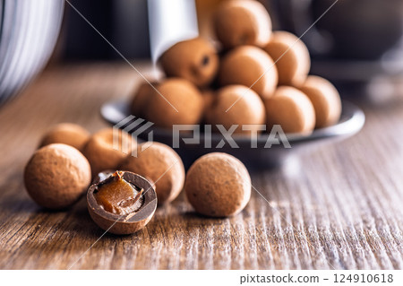 Chocolate truffles with cocoa powder and caramel filling on wooden table. 124910618