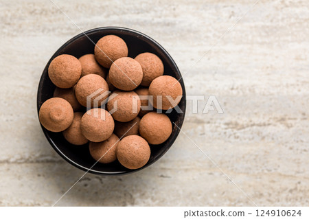 Chocolate truffles with cocoa powder in bowl on kitchen table. Top view. Chocolate truffles with cocoa powder in bowl on kitchen table. Top view. 124910624